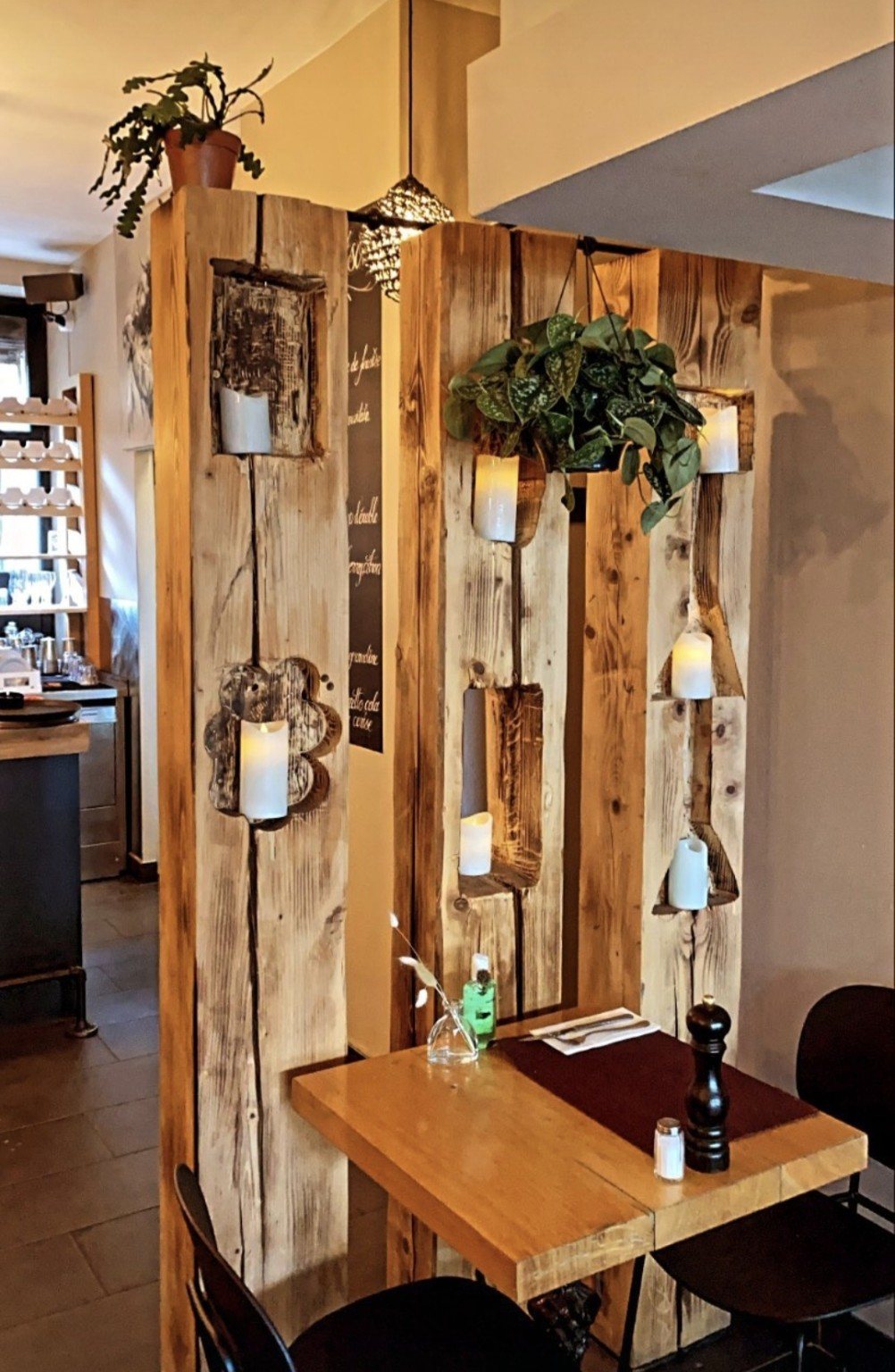 Cloison de bois brut, bougies et table dressée dans la salle.